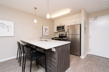 A kitchen with a white countertop and black barstools.
